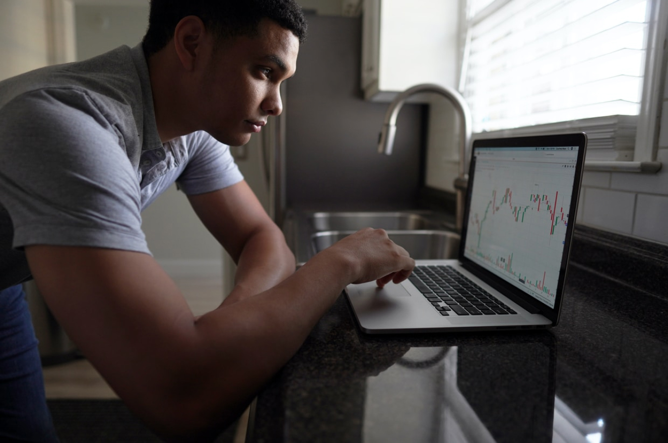 Man bent over on desk looking at laptop screen